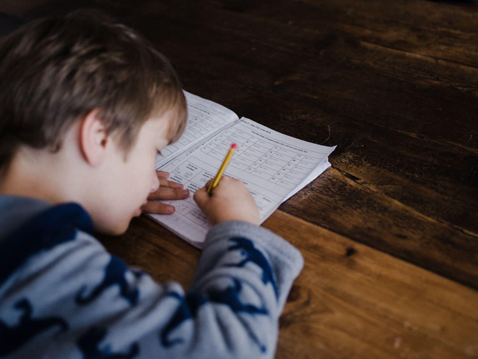 Happy child doing math on paper, surrounded by math symbols